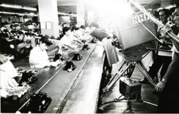 ベルトコンベアでの電話機生産 NHKで紹介される工場（昭和30年）（写真提供：岩崎通信機株式会社）