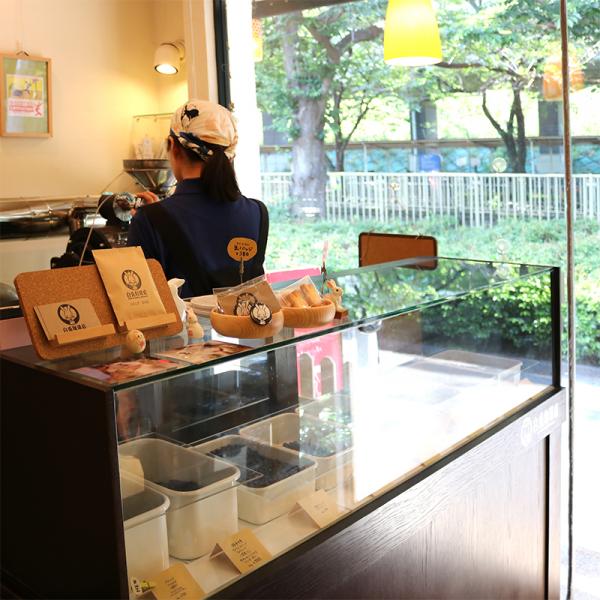 神田川遊歩道の木漏れ日が差し込む店内。焙煎機が目をひく。コーヒーのほか、ウサギクッキー（200円）やオリジナル缶バッジ（380円）なども販売