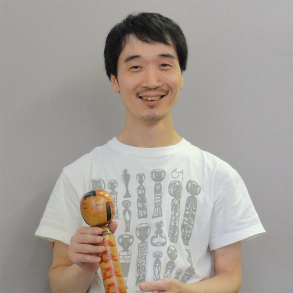 お気に入りのこけしを持つ山藤輝之さん。こけしのTシャツはCOCHAE（※２）のデザイン