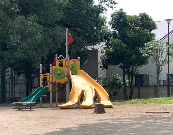 広場の周囲に、バナナ型のすべり台やブランコ、幼児用の遊具コーナーがある