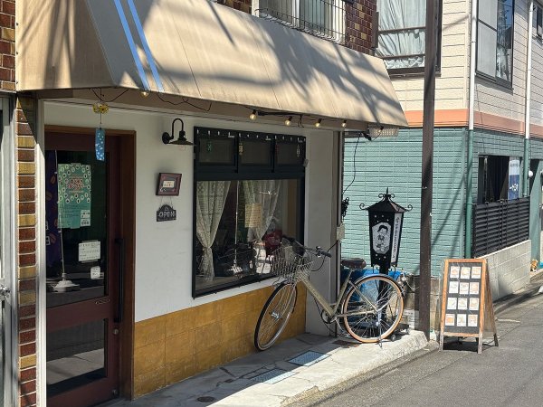 店舗外観。左右に店主夫婦のイラストが入った電飾看板が目印