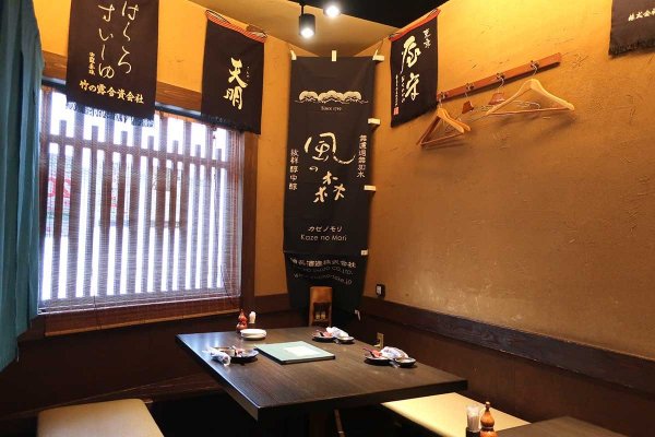 テーブル席には蔵元の前掛けが飾られており、日本酒文化が感じられる