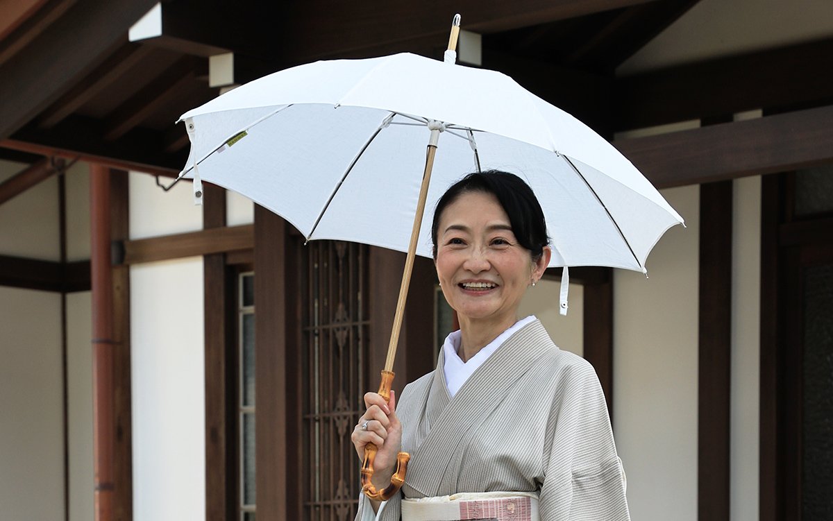 荻外荘の玄関前に立つ天野さん。お気に入りの日傘を差して（撮影：やまかわけんいちさん）