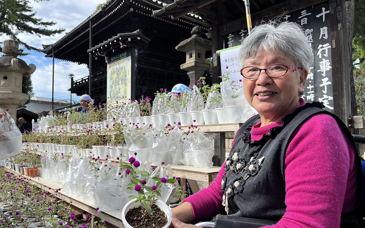 「千日紅市（せんにちこういち）」で、育てた千日紅の配布を見守る山田さん